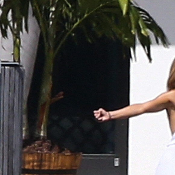 Jennifer Lopez fait des étirements pieds nus devant la maison qu'elle partage avec Ben.Affleck à Miami le 25 mai 2021.Elle porte une combinaison large à bretelles. 