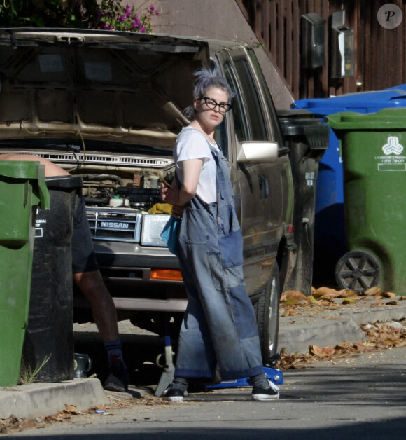 Kelly Osbourne aide son compagnon Erik Bragg à réparer sa voiture sur un trottoir de Los Angeles.