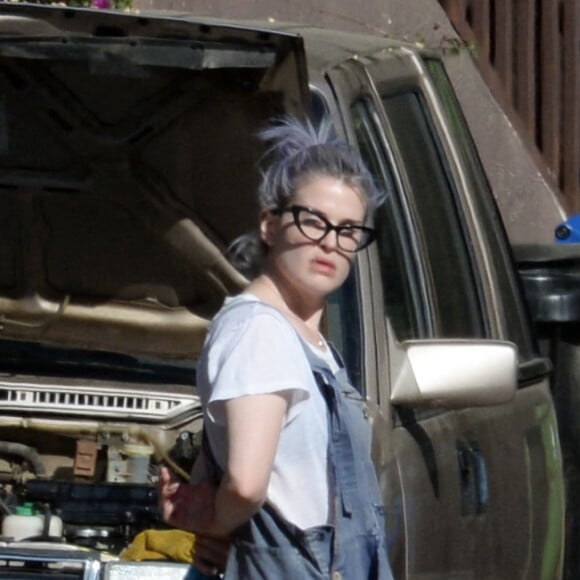 Kelly Osbourne aide son compagnon Erik Bragg à réparer sa voiture sur un trottoir de Los Angeles.