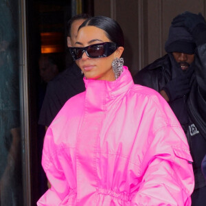 Kim Kardashian (emmitouflée dans un long manteau rose) et Kanye West sortent ensemble de l'hôtel Ritz Carlton pour se rendre dans les studios de l'émission "Saturday Night Live" (SNL) à New York, le 9 octobre 2021.
