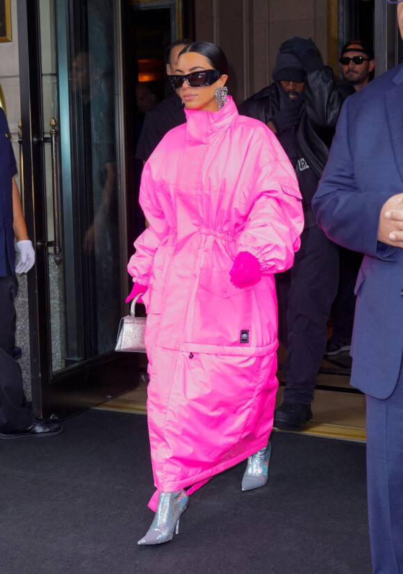 Kim Kardashian (emmitouflée dans un long manteau rose) et Kanye West sortent ensemble de l'hôtel Ritz Carlton pour se rendre dans les studios de l'émission "Saturday Night Live" (SNL) à New York, le 9 octobre 2021.