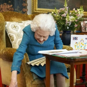 La reine Elisabeth II est rejointe par l'un de ses chiens, un Dorgi appelé Candy, alors qu'elle regarde une exposition de souvenirs de ses jubilés d'or et de platine dans la salle Oak du château de Windsor 2022.