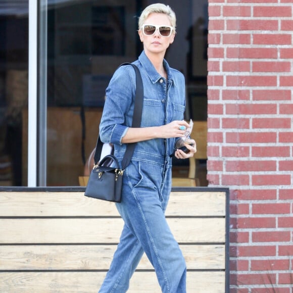 Exclusif - Charlize Theron porte une combinaison pantalon en jean et des bottines en daim pour aller déjeuner au restaurant Sugarfish à Los Angeles, le 3 mars 2020.