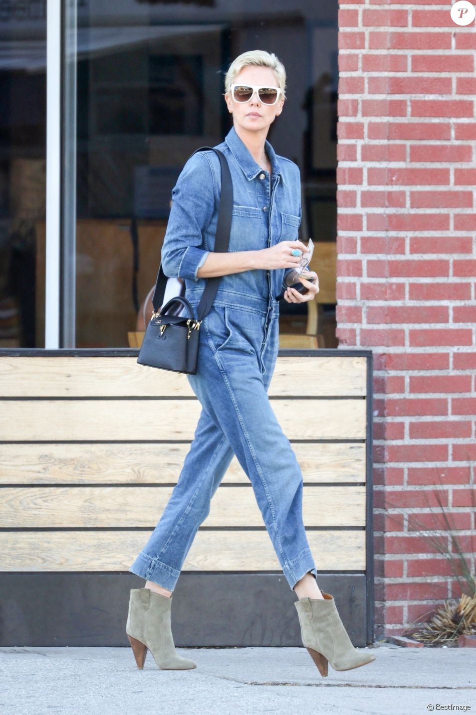 Exclusif - Charlize Theron porte une combinaison pantalon en jean et des bottines en daim pour aller déjeuner au restaurant Sugarfish à Los Angeles, le 3 mars 2020.
