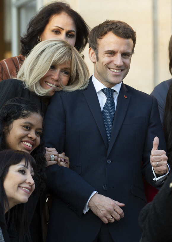 Le président de la République française, Emmanuel Macron et sa femme la Première Dame, Brigitte Macron posent pour une photo de groupe avec les premières lauréates de l'Initiative Marianne pour les défenseurs des droits de l'homme à la suite d'une cérémonie de remise de prix dans le cadre de la journée internationale de la femme, au palais de l'Elysée à Paris, France, le 8 mars 2022