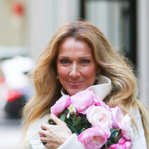 Celine Dion rayonnante et très souriante dans un ensemble pull écru et jupe bouffante fleurie salue ses fans à la sortie de son hôtel à New York, le 8 mars 2020 