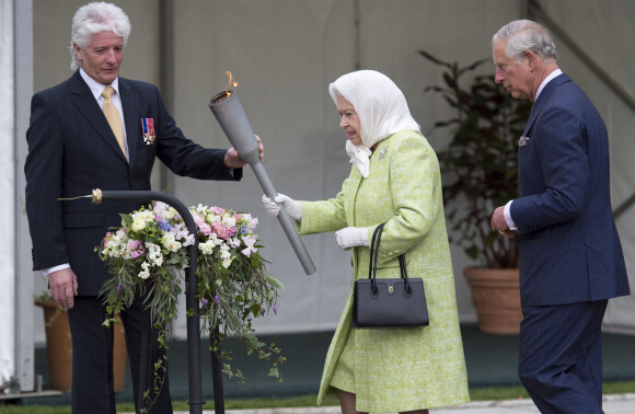 La reine Elisabeth II d'Angleterre, accompagnée de son fils le prince Charles, allume un flambeau au château de Windsor, à l'occasion de son 90ème anniversaire. 