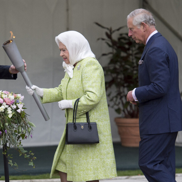 La reine Elisabeth II d'Angleterre, accompagnée de son fils le prince Charles, allume un flambeau au château de Windsor, à l'occasion de son 90ème anniversaire. 