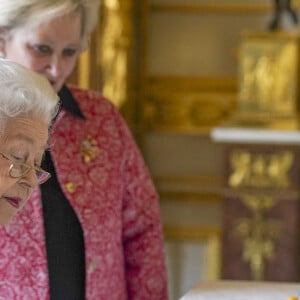 La reine Elisabeth II d'Angleterre parcourt l'exposition d'objets de la société d'artisanat britannique Halcyon Days, pour marquer son jubilé de platine, au château de Windsor, le 23 mars 2022. 