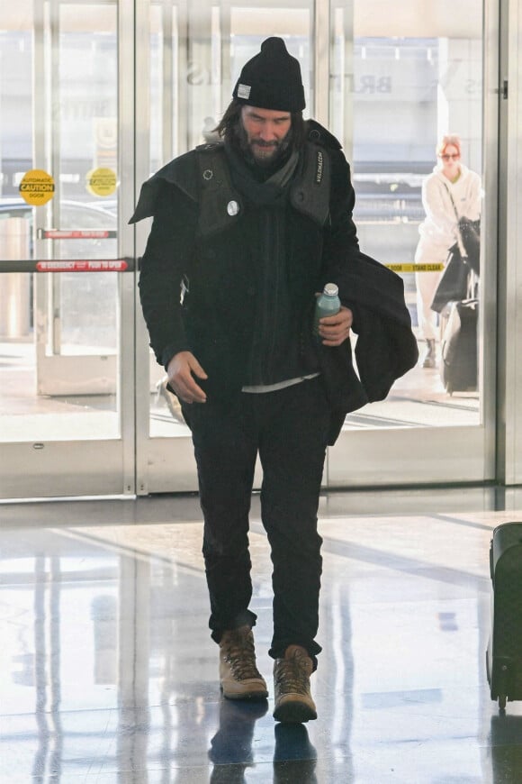 Keanu Reeves arrive à l'aéroport JFK de New York City, New York, Etats-Unis, le 30 décembre 2022. Keanu porte un bonnet noir assorti à son ensemble tout en noir et à des bottes. 