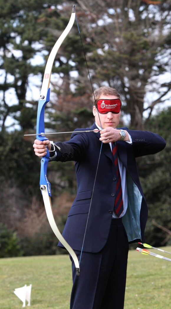 Le Prince William fait du tir à l'arc avec un masque sur les yeux. 22/02/2010