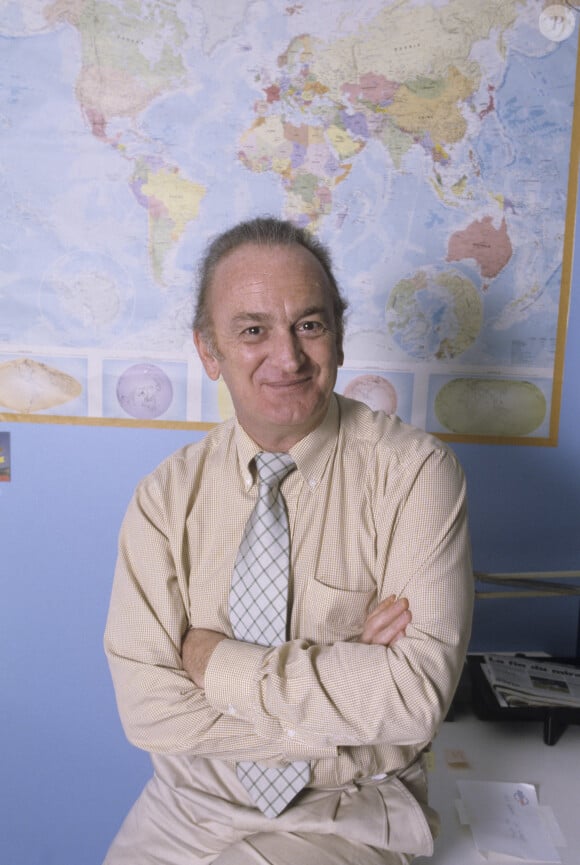 Archives - En France, à Paris, Alain Gillot-Petre devant une carte du monde affichée au mur.