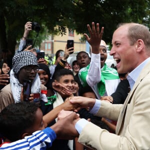 Le prince William, prince de Galles, salue les sympathisants lors d'une visite à l'association Reach Up Youth au centre Verdon Recreation à Sheffield, Royaume-Uni, le 27 juin 2023, pour mettre en lumière comment les sports de base peuvent connecter les jeunes à leurs communautés, en renforçant le soutien des pairs, dans le cadre de sa tournée du Royaume-Uni pour lancer un projet visant à mettre fin à l'itinérance. 