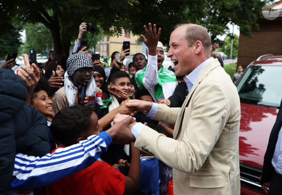 Le prince William, prince de Galles, salue les sympathisants lors d'une visite à l'association Reach Up Youth au centre Verdon Recreation à Sheffield, Royaume-Uni, le 27 juin 2023, pour mettre en lumière comment les sports de base peuvent connecter les jeunes à leurs communautés, en renforçant le soutien des pairs, dans le cadre de sa tournée du Royaume-Uni pour lancer un projet visant à mettre fin à l'itinérance. 