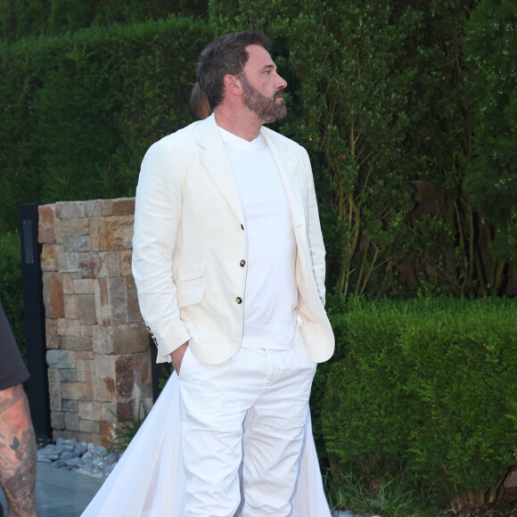 Ben Affleck portait un blazer couleur crème sur un t-shirt blanc, assorti d'un pantalon blanc et de baskets blanches elles aussi
Jennifer Lopez, Ben Affleck et leur famille arrivent à la fête du 4 juillet de Michael Rubin dans son domaine des Hamptons