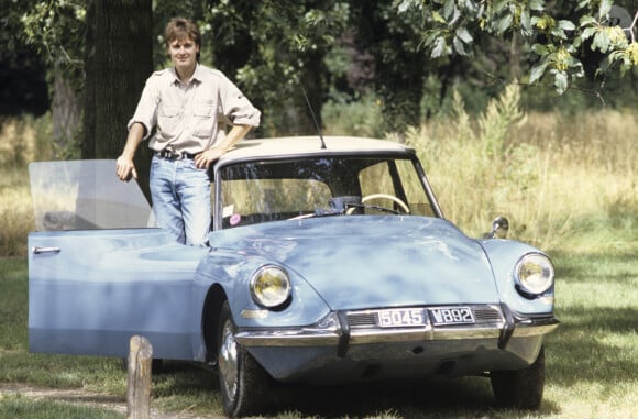 En France, en région parisienne, Thierry Hazard sur le bas de caisse de sa voiture DS bleue en août 1991.