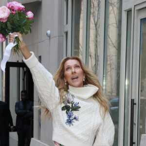 Celine Dion rayonnante et très souriante dans un ensemble pull écru et jupe bouffante fleurie salue ses fans à la sortie de son hôtel à New York, le 8 mars 2020