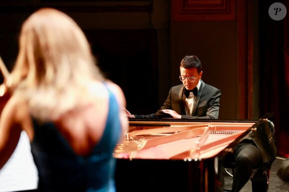 Le compositeur et pianiste de renommée internationale Omar Harfouch a joué en première mondiale sa nouvelle création “Concerto pour la paix” avec l'Orchestre Méditerranéen de Béziers, composé de 43 musiciens et du chef d'orchestre Mathieu Bonin, accompagné au violon par la célèbre violoniste Anne Gravoin. Les spectateurs du théâtre municipal de Béziers, un des plus vieux théâtre à l’italienne en France, ont applaudi Omar Harfouch en standing ovation après le concert. Avant d’interpréter sa nouvelle oeuvre, Omar Harfouch a prononcé un discours émouvant dans lequel il a rappelé son enfance à Tripoli et a présenté au public son ami d'enfance, le maestro Hataf Khoury, qui a participé à l’orchestration. “Pourquoi Concerto pour la Paix ? Je suis né au Liban dans la ville de Tripoli. Tout au long de mon enfance et de mon adolescence, je n'ai vu que la guerre civile qui a ravagé mon pays d'origine. J'ai survécu grâce au piano. Il était mon refuge et m'a sauvé la vie. Il était donc naturel pour moi d’écrire pour la paix et de raconter que seule la paix peut sauver nos enfants et nos petits-enfants et rien d’autre. Devant vous se trouve un orchestre qui comprend 45 musiciens, et je ne leur ai pas demandé d'où ils viennent ni quelle est leur religion ou leur appartenance politique. Tout ce qui nous importait lors de nos journées de répétition, c’était de jouer en harmonie, de jouer avec transparence, de jouer juste et avec notre cœur, car tout ce qui comptait c’était de jouer ensemble et de donner de l’espoir aux autres. Seule la musique peut transmettre la paix, et seule la musique peut changer l’histoire.” © Daniel Topic via Bestimage  World-renowned composer and pianist Omar Harfouch gave the world premiere of his new work "Concerto pour la paix" with the Orchestre Méditerranéen de Béziers, comprising 43 musicians and conductor Mathieu Bonin, accompanied on violin by the famous violinist Anne Gravoin. The audience at the Théâtre Municipal de Béziers, one of the oldest Italian-style theatres in France, gave Omar Harfouch a standing ovation after the concert. Before performing his new work, Omar Harfouch gave a moving speech in which he recalled his childhood in Tripoli and introduced the audience to his childhood friend, maestro Hataf Khoury, who took part in the orchestration. "Why Concerto for Peace? I was born in Lebanon in the city of Tripoli. Throughout my childhood and adolescence, all I saw was the civil war that ravaged my homeland. I survived thanks to the piano. It was my refuge and saved my life. So it was natural for me to write for peace and to say that only peace can save our children and grandchildren, and nothing else. In front of you is an orchestra of 45 musicians, and I haven't asked them where they come from or what their religion or political affiliation is. All that mattered to us during our days of rehearsal was to play in harmony, to play with transparency, to play fairly and with our hearts, because all that mattered was to play together and to make a difference. 