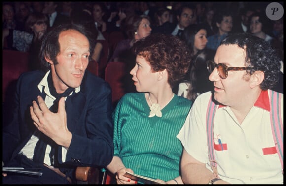 Notamment le fait de se rendre régulièrement dans leur maison de vacances 
Archives - Rufus, Coluche et sa femme Véronique Colucci au Festival de Cannes. Mai 1976.