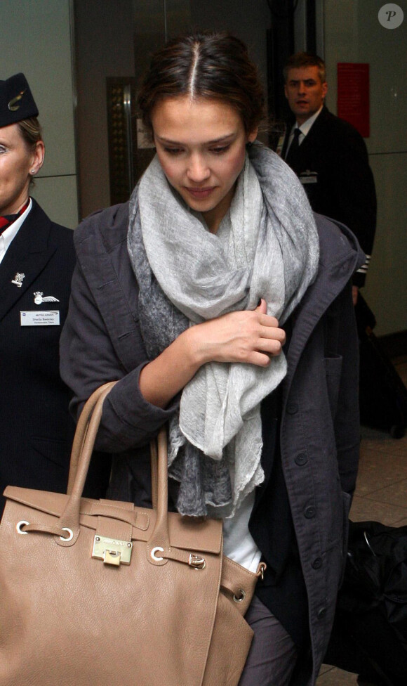 Jessica Alba arrive à Londres escortée par deux hôtesses de la British Airways, le 12 février 2011. Elle porte un sac Jimmy Choo, modèle Rhys.