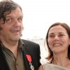 Emir Kusturica prend la pose aux côtés de son épouse Maja après avoir été fait Chevalier dans l'Ordre de la Légion d'Honneur par le ministre de la culture Frédéric Mitterrand au Café des Palmes dans le Palais des Festivals lors du 64e Festival de Cannes le 13 mai 2011
