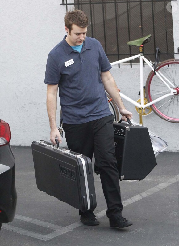 Un vendeur avec les achats de Brad Pitt et son fils Maddox à la sortie d'un magasin de guitares, à Los Angeles, le 1er mars 2012.