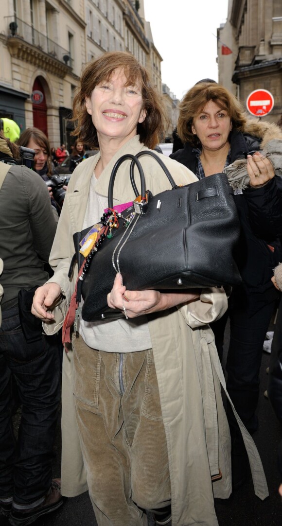 Tenant un Birkin customisé par différents accessoires, Jane Birkin arrive au défilé Hermès à l'École Nationale des Beaux-Arts. Paris, le 4 mars 2012.