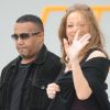 Mariah Carey au bras de son garde du corps, sourit aux photographes venus suivre son départ de la France. Aéroport du Bourget, le 29 avril 2012.