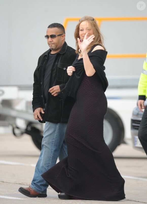 Mariah Carey au bras de son garde du corps, sourit aux photographes venus suivre son départ de la France. Aéroport du Bourget, le 29 avril 2012.