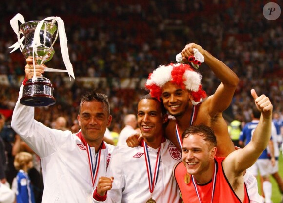 Robbie Williams et son équipe d'Angleterre brandissent leur trophée à l'issue du match de charité Soccer Aid 2012 à Old Trafford. Manchester, le 27 mai 2012.