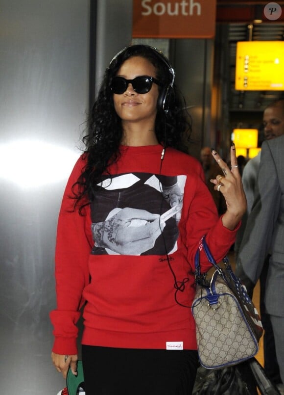 Rihanna habillée d'un pull Diamond Supply Co., lance un "Deuces" aux photographes à son arrivée à l'aéroport d'Heathrow. Londres, le 27 août 2012.