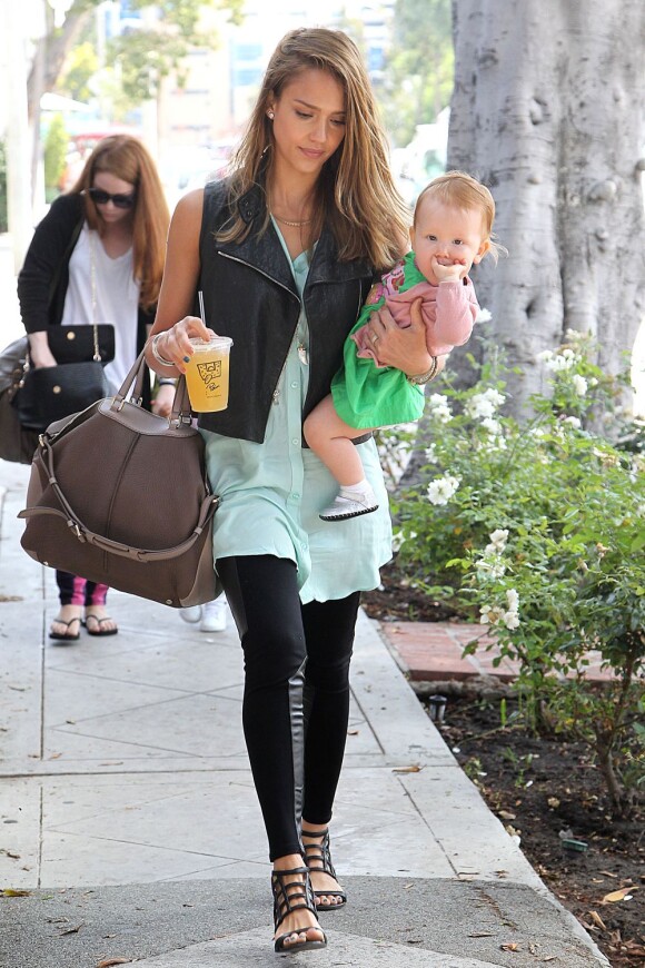 Jessica Alba, les bras chargés par son sac Tod's, une boisson et sa fille Haven, porte un chemisier vert menthe Rails, un legging Nebula de Kymerah et des sandales Surface To Air. Los Angeles, le 24 août 2012.