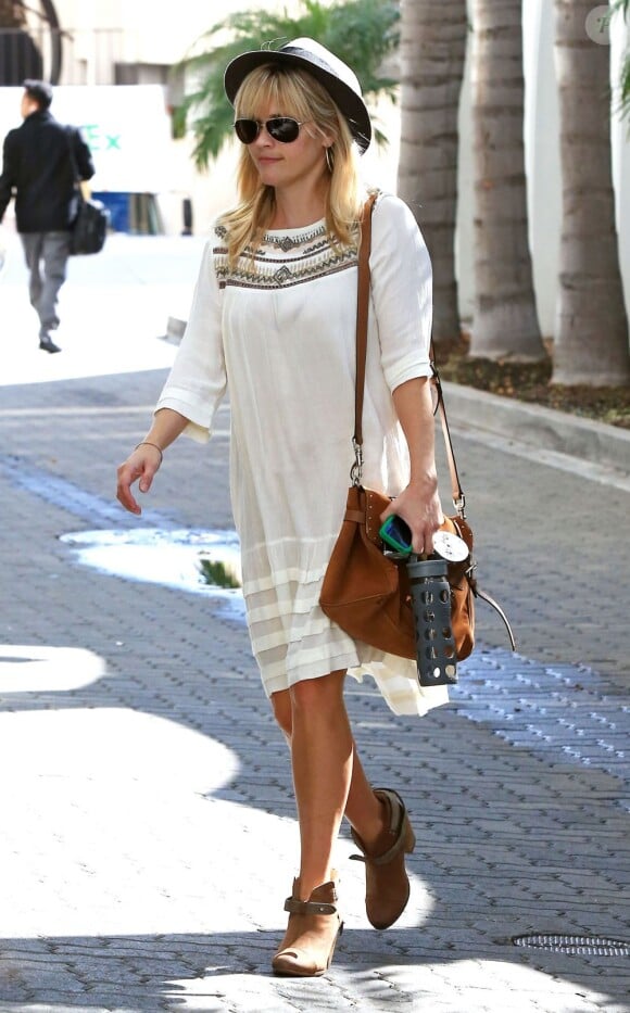 Look bohème parfait pour Reese Witherspoon qui accessoirise sa robe blanche avec des low-boots, un chapeau et un sac Mulberry