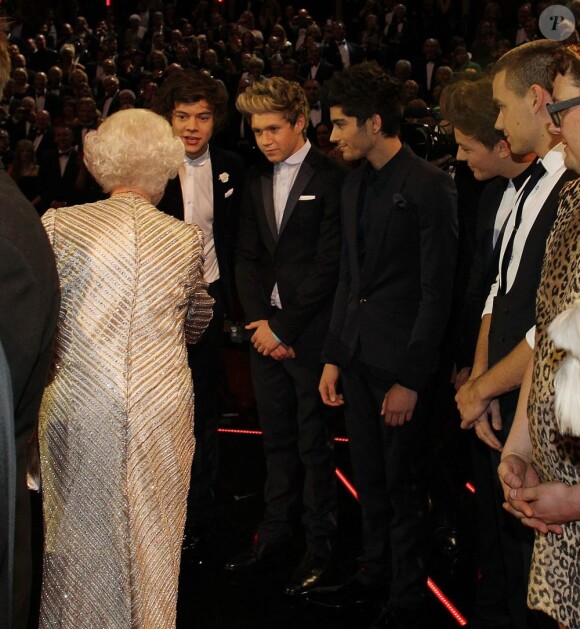 La reine Elizabeth II salue les One Direction au 100e gala du Royal Variety au Royal Albert Hall, à Londres, le 19 novembre 2012, en présence de la reine Elizabeth II et du prince Philip.