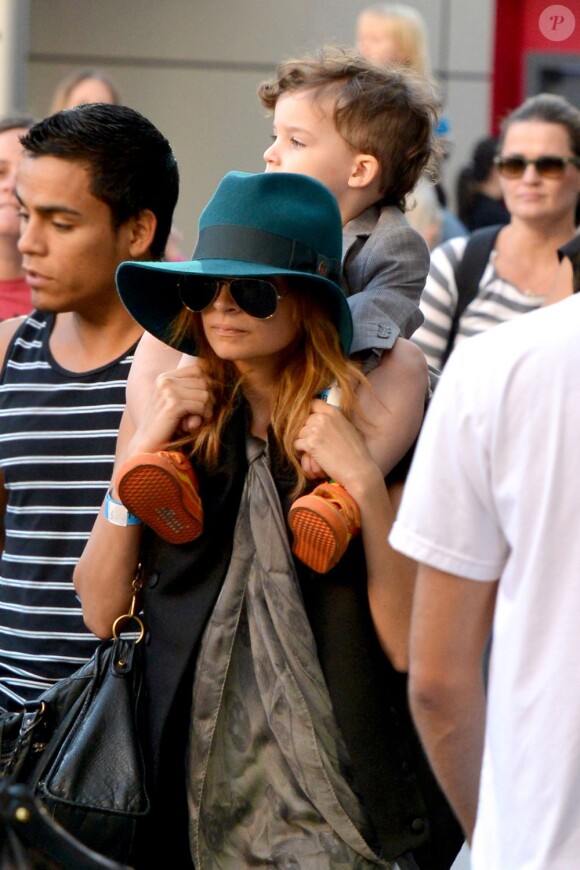 Nicole Richie se glisse parmi les visiteurs anonymes du Nokia Theater avec son fils Sparrow (trois ans) sur les épaules. Los Angeles, le 23 novembre 2012.