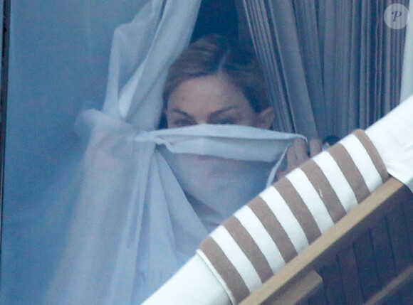 Madonna se cache derrière les rideaux de sa chambre d'hôtel à Rio de Janeiro, le 1er décembre 2012.