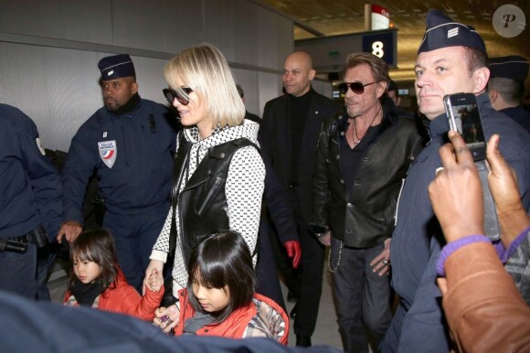 Johnny Hallyday et Laeticia, accompagnés de leurs fillettes à l'aéroport de Roissy pour prendre un avion et rejoindre Los Angeles, le 10 février 2013.