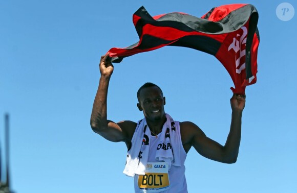 Usain Bolt avec un drapeau de Flamengo sur la plage de Copacabana à Rio le 31 mars 2013.