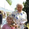 Elizabeth II posant avec la jeune Jessica Fitch et son ourson Bertie,  le 11 juillet 2013 au premier jour du Coronation Festival organisé à Buckingham Palace par la Royal Warrants Holders Association à l'occasion des 60 ans du couronnement de la reine.