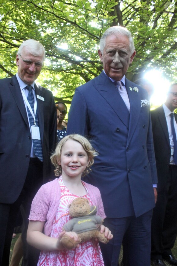 Le prince Charles posant avec la jeune Jessica Fitch et son ourson Bertie,  le 11 juillet 2013 au premier jour du Coronation Festival organisé à Buckingham Palace par la Royal Warrants Holders Association à l'occasion des 60 ans du couronnement d'Elizabeth II.