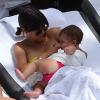 Kourtney Kardashian se relaxe avec son fiancé Scott Disick et leurs enfants Mason et Penelope au bord d'une piscine à Miami, le 20 juillet 2013. L'aînée du clan Kardashian donne le sein à la petite Penelope.