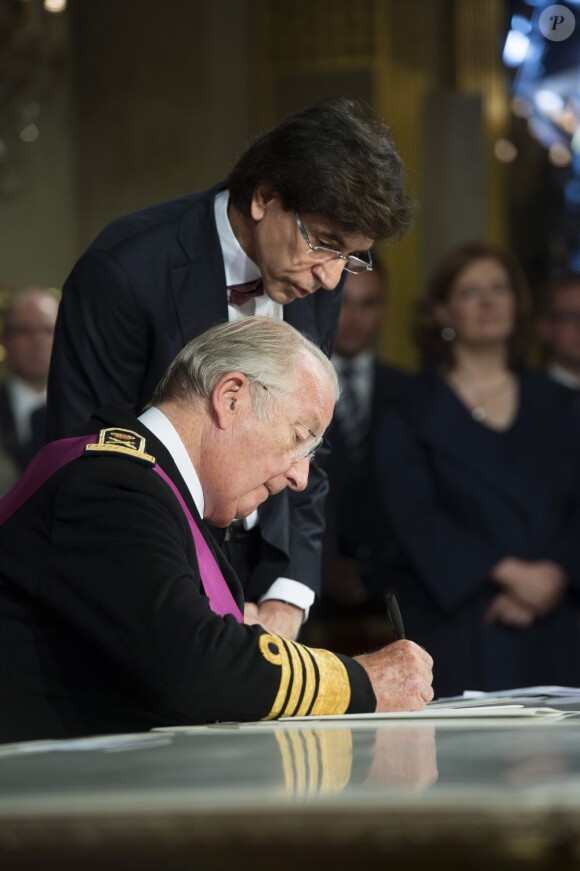 Le roi Albert II signe son acte d'abdication sous le regard de l'élégant Premier ministre Elio Di Rupo, à Bruxelles, le 21 juillet 2013.