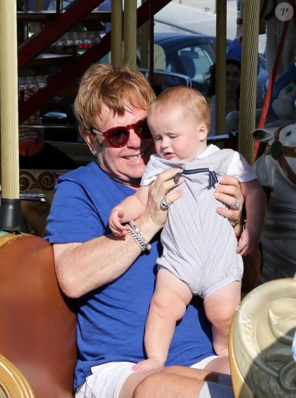 Le chanteur Elton John et son mari David Furnish s'amusent sur un manège avec leurs deux fils Elijah et Zachary, pendant leurs vacances en famille à Saint-Tropez. Le 22 août 2013.