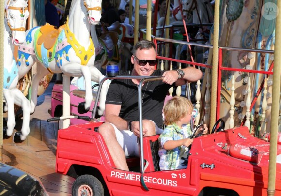 Elton John et son mari David Furnish s'amusent sur un manège avec leurs deux fils Elijah et Zachary, pendant leurs vacances à Saint-Tropez. Le 22 août 2013.