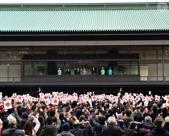 salue depuis un balcon du palais la foule venue nombreuse pour célébrer le 80e anniversaire de l'empereur, à Tokyo le 23 décembre 2013.