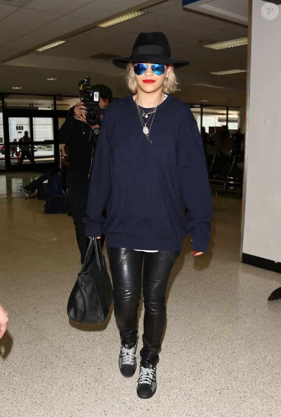 Rita Ora à l'aéroport de Los Angeles, habillée d'un pull bleu marine, d'un pantalon en cuir Balmain, d'un sac Hermès et de baskets Adidas. Le 13 janvier 2014.
