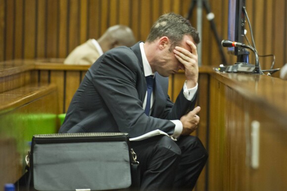 Oscar Pistorius, prostré sur le banc des accusés avec son seau à ses côtés, écoute les témoins défilés à la barre durant son procès pour meurtre, le 12 mars 2014