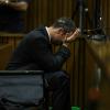 Oscar Pistorius, prostré sur le banc des accusés avec son seau à ses côtés, écoute les témoins défilés à la barre durant son procès pour meurtre, le 12 mars 2014