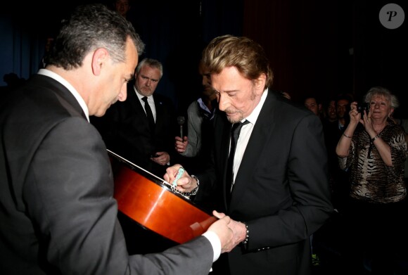 Johnny Hallyday signe un autographe à l'avant-première du film Salaud on t'aime à l'UGC Normandie sur les Champs-Elysées à Paris le 31 mars 2014.