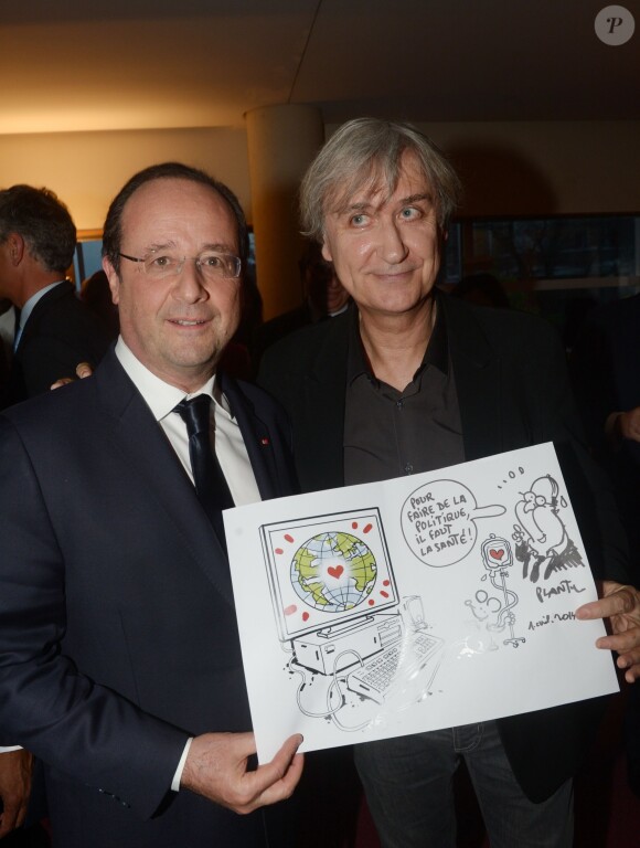 François Hollande prend la pose avec le dessin que lui a offert le dessinateur Plantu au dîner en l'honneur d'UNITAID au Conseil économique, social et environnemental à Paris, le 1er avril 2014.